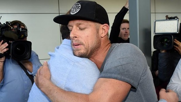Mick Fanning is hugged after arriving at Sydney Airport after being attacked by a shark